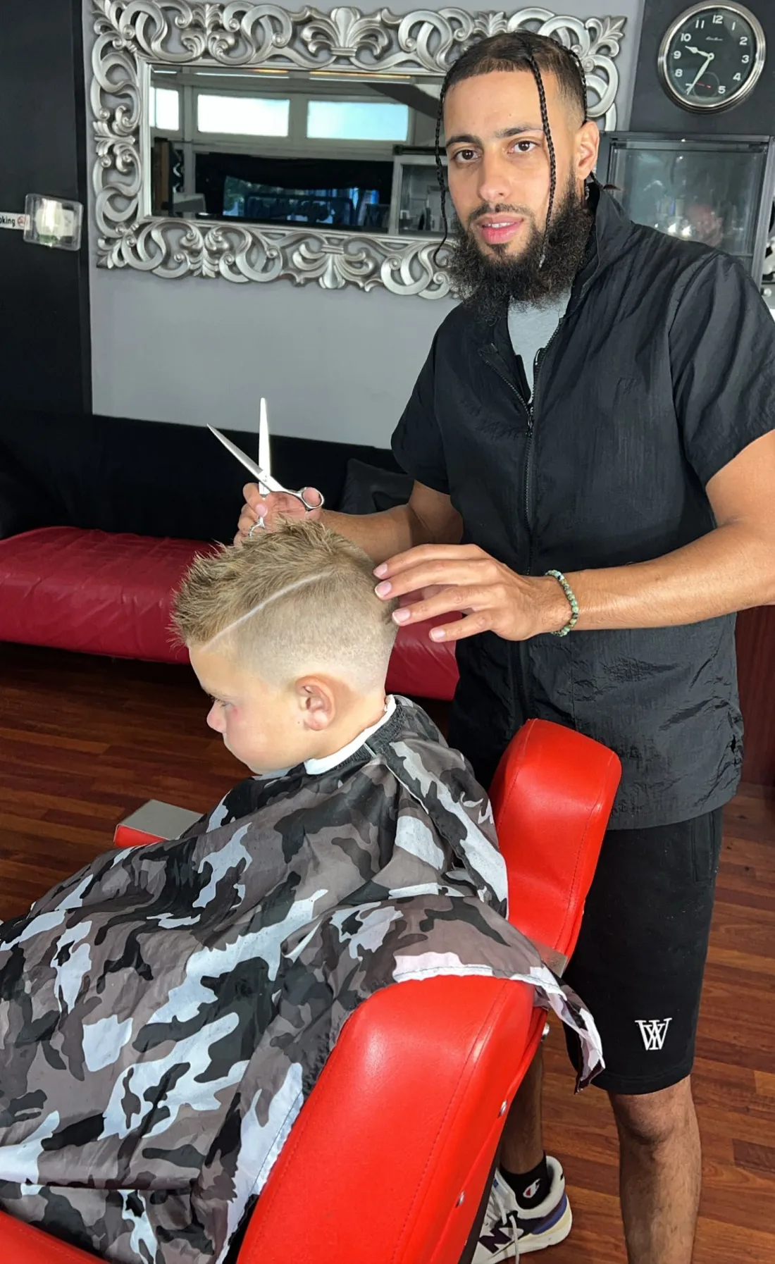 A Blades Edge barber cutting a young client's hair